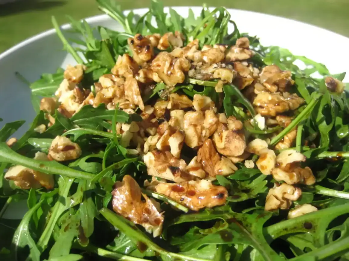 Ensalada de rucula fresca con nueces tostadas y un glaseado balsámico. Un plato ligero y sabroso.