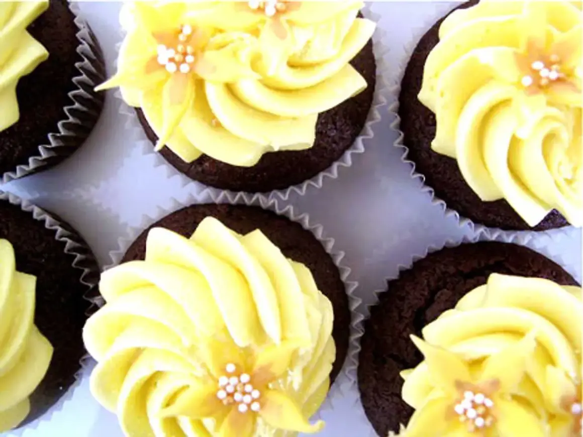 Chokladmuffins med gul frosting och blomsterdekoration. En härlig syn av frosting muffins som ser aptitliga ut.