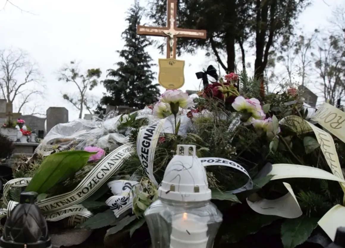 Wieniec pogrzebowy z krzyżem i płonącą świecą na cmentarzu.