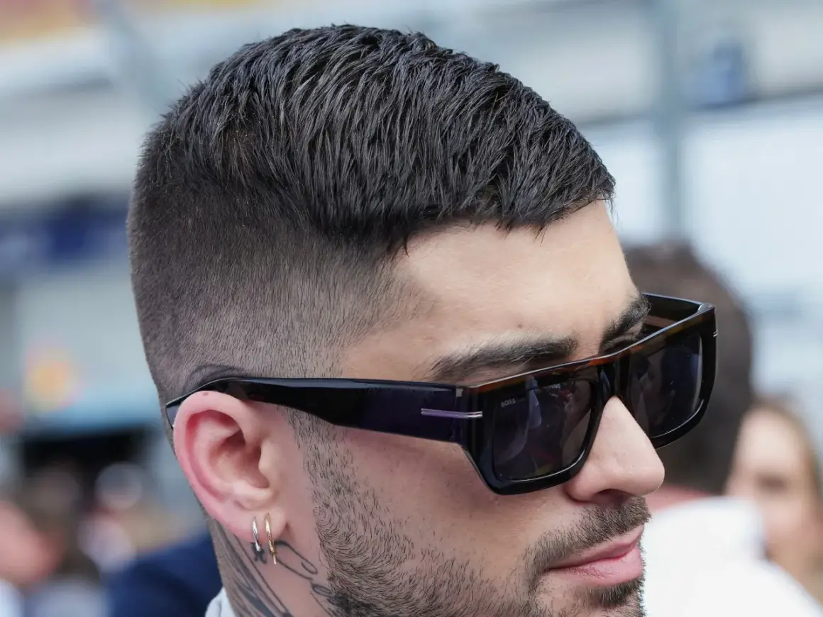 Nahaufnahme eines Mannes mit kurz geschnittenem, dunklem Haar und Sonnenbrille. Sein moderner herren haarschnitt ist perfekt gestylt.
