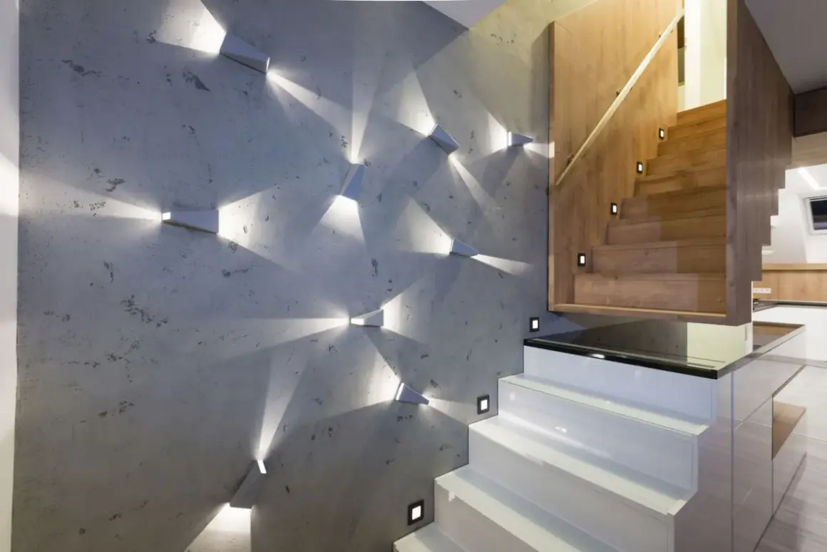 Moderne Wandgestaltung mit geometrischen Spots, die Lichtmuster auf Beton werfen. Perfekte Wand-Inspo für einen stilvollen Treppenaufgang.