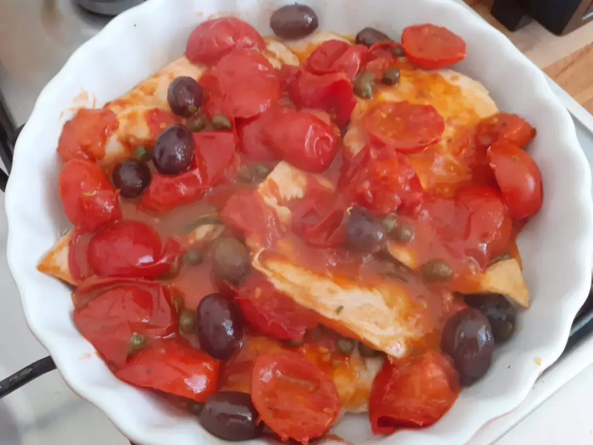 Petto di pollo alla pizzaiola in teglia, con pomodorini, olive nere e capperi. Un piatto saporito e colorato.