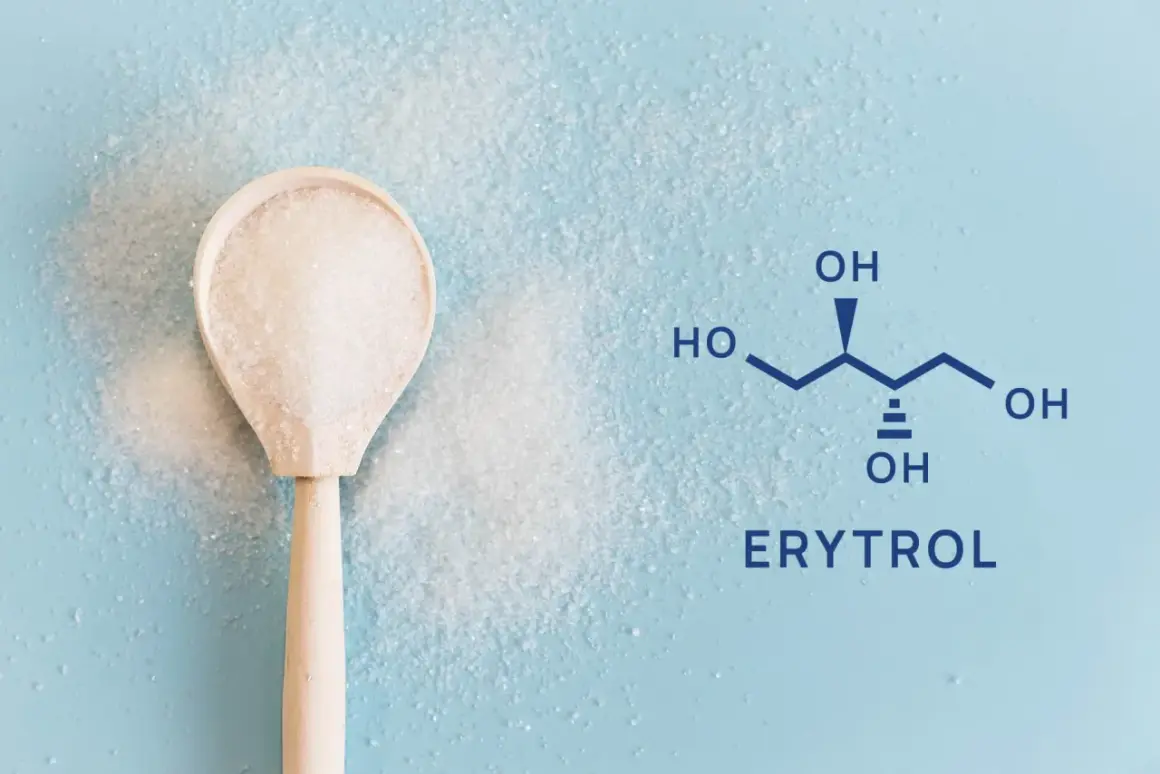 Drewniana łyżka z kryształkami erytrolu obok wzoru chemicznego. Erytrytol to zdrowa alternatywa dla cukru.