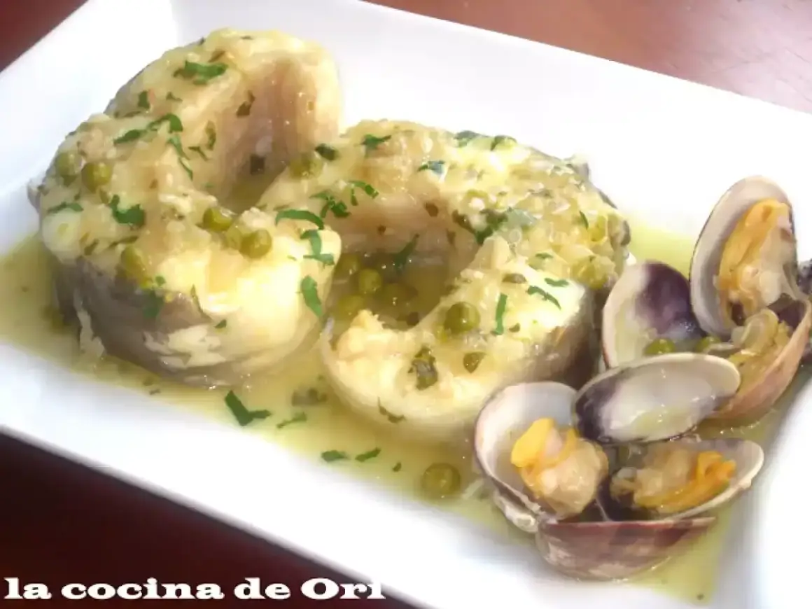 Congrio en salsa verde con guisantes y almejas, un plato delicioso y lleno de sabor.
