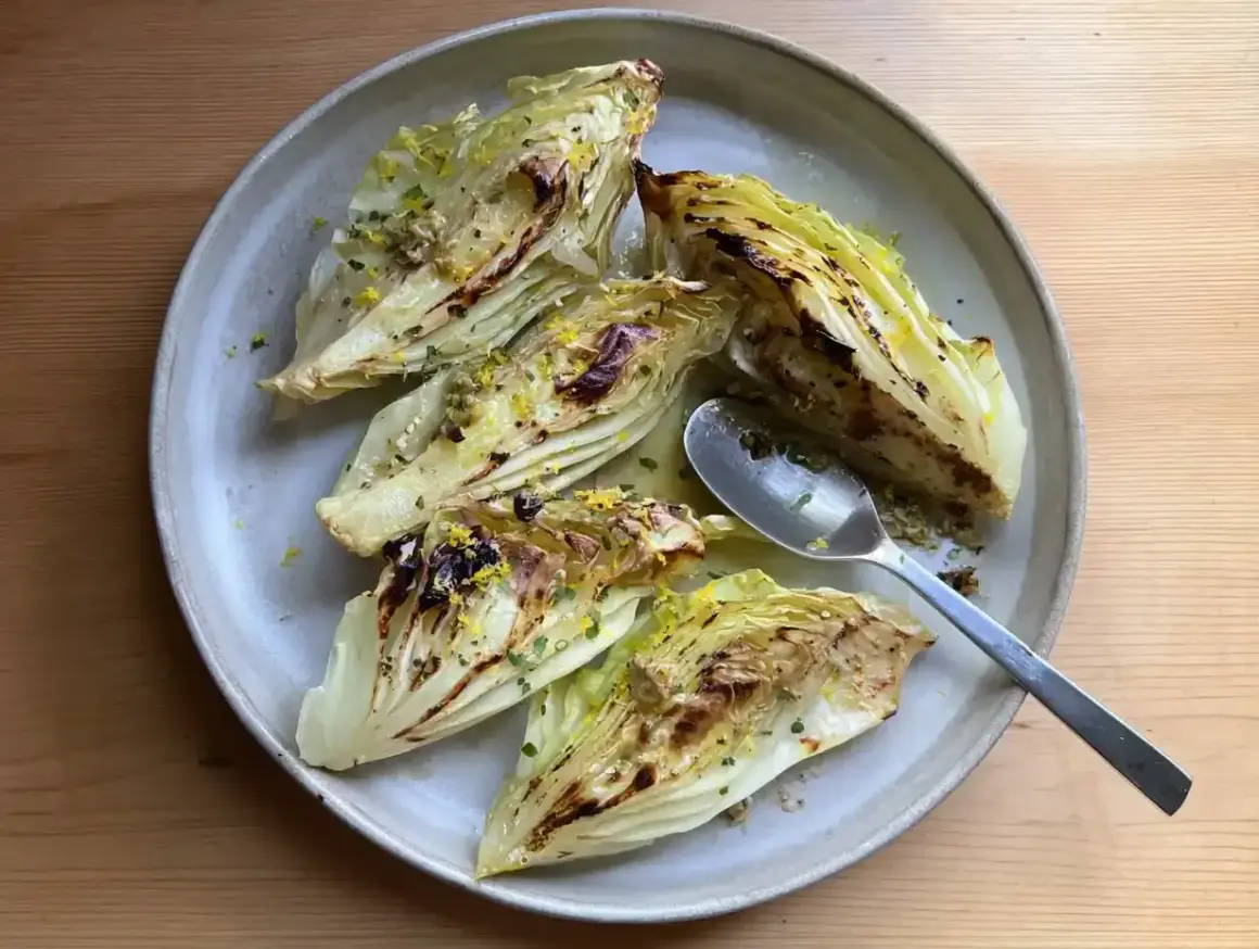 Grilla spetskål med citron och örter, serverad på en ljusgrå tallrik med en sked.