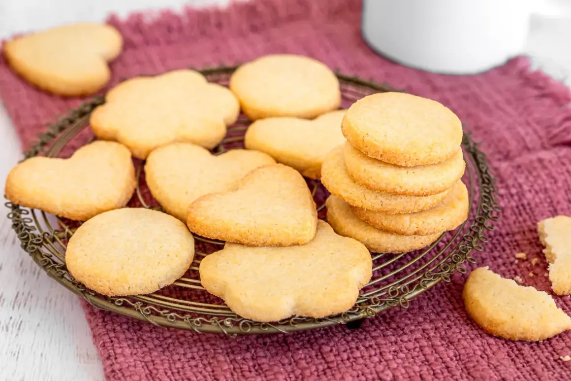 Deliziosi dolci da fare in casa, biscotti a forma di cuore e fiori su un cestino di metallo, pronti per essere gustati.
