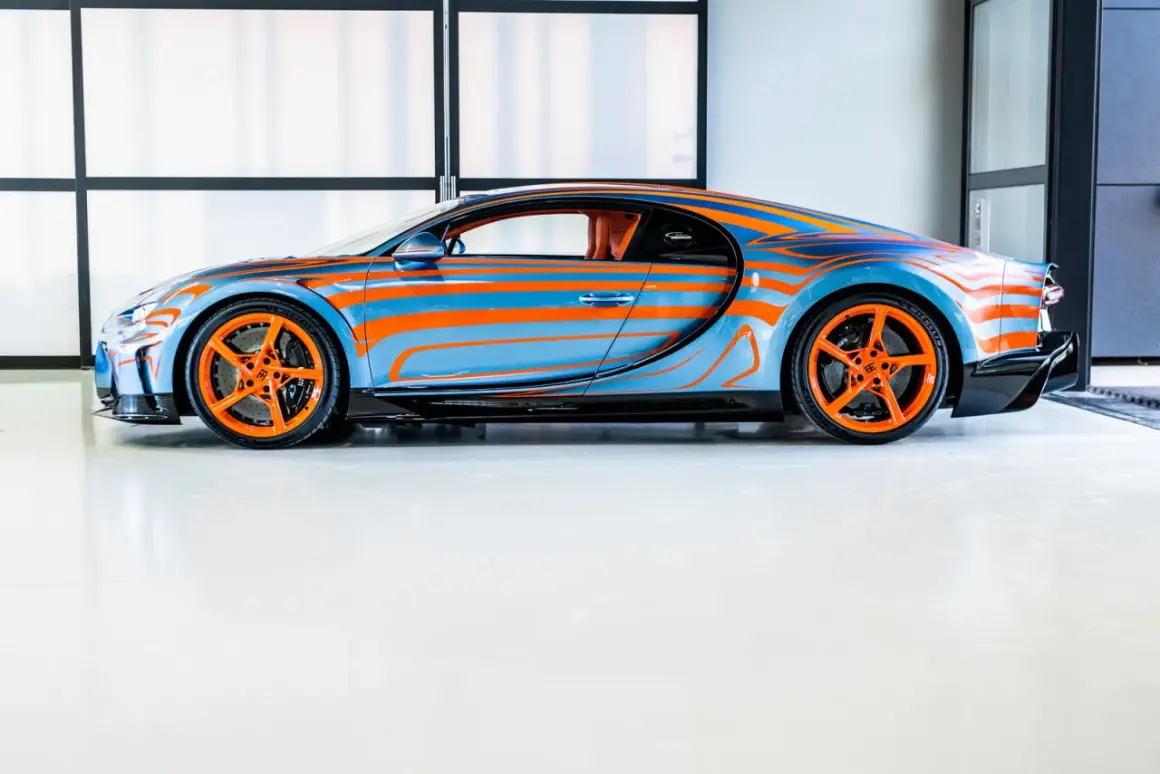 Niebiesko-pomarańczowy Bugatti Chiron Super Sport z dynamicznym wzorem falistych linii i pomarańczowymi felgami.
