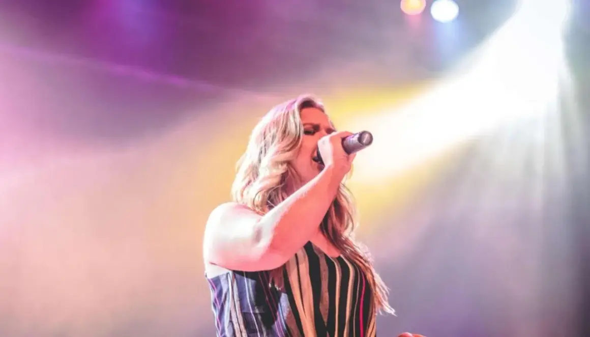 Cantante italiana sul palco, illuminata da luci soffuse. Immagina il suo cachet listino prezzi cantanti italiani.
