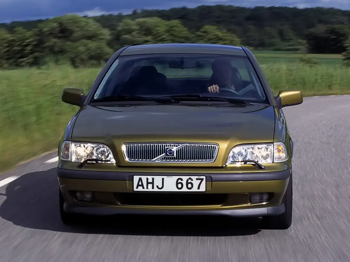 Złoty Volvo S40 jedzie po wiejskiej drodze. Skąd jest to Volvo? Z pewnością z krainy spokoju i zieleni.