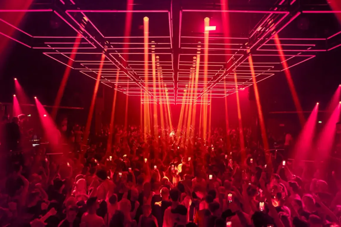 Folla in delirio sotto un gioco di luci rosse e laser al **Hï Ibiza**. L'energia della notte vibra tra la gente.