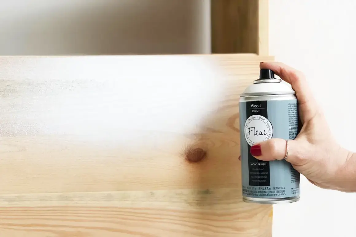 Mano spruzza primer legno per preparare la superficie prima della verniciatura. Utile per uniformare e far aderire meglio il colore.