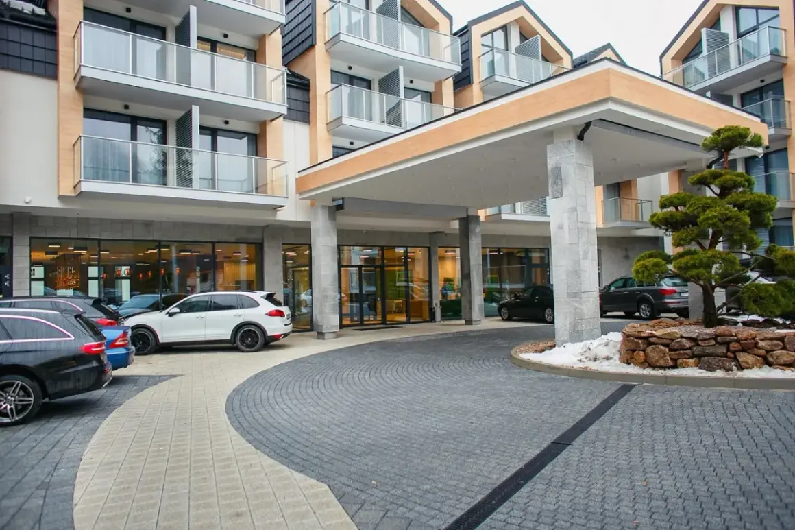 Nowoczesny hotel z parkingiem i drzewkiem bonsai.