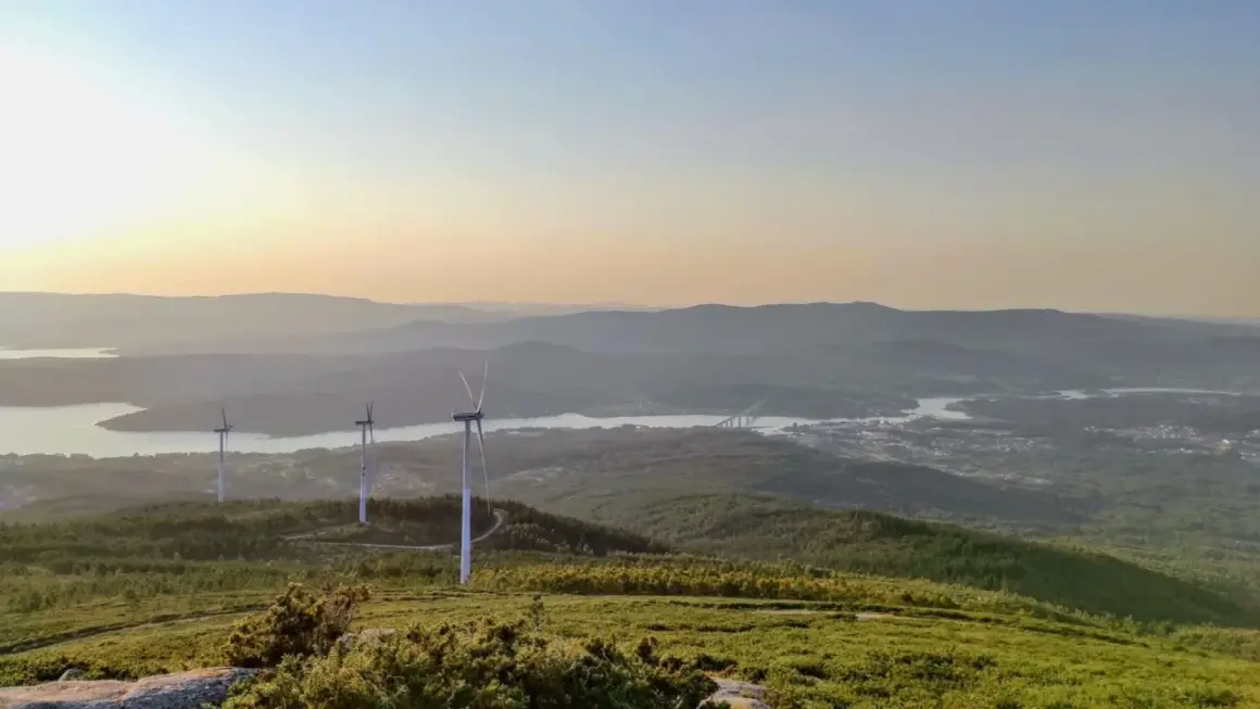 Vistas del monte Xiabre con molinos de viento y un río al atardecer.