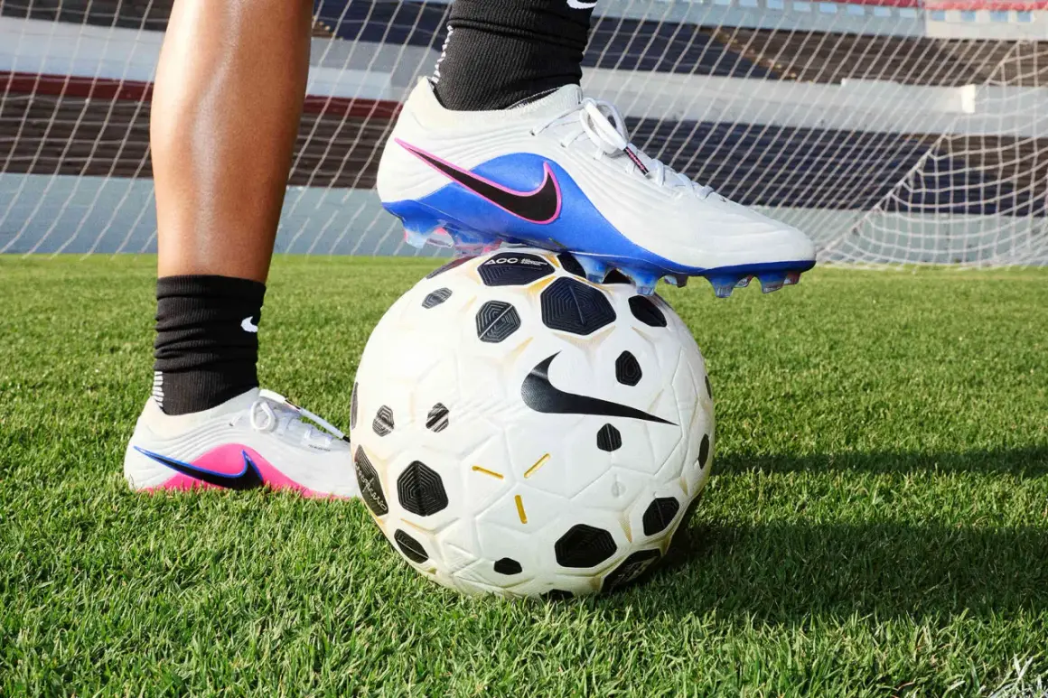 Un pied en crampons de foot, posé sur un ballon, sur l'herbe. Peut-on laver des chaussures de foot en machine ?
