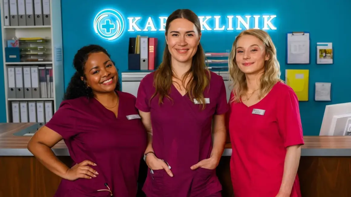 Drei Krankenschwestern lächeln vor dem Schild "Klinik". Staffel 12 von Bettys Diagnose verspricht spannende Fälle.