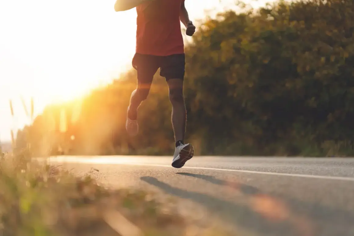 Läufer auf einer Straße im Sonnenuntergang, intensive **Vorbereitung Halbmarathon**.