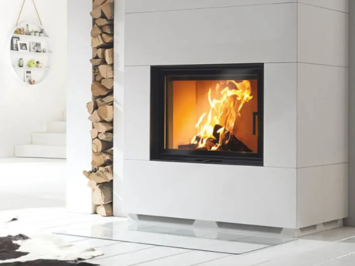 Moderner Kamin mit brennendem Feuer. Holzstapel daneben. Unterschied zwischen Zeitbrand und Dauerbrand ist hier nicht ersichtlich.