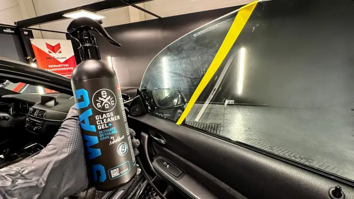 Rękawica z preparatem SWAG Glass Cleaner Gel pokazuje, czym umyć szyby w samochodzie. Żółta taśma na szybie wyznacza obszar czyszczenia.