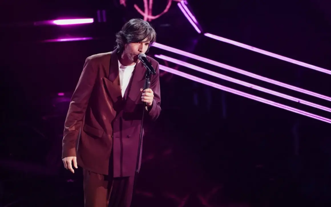 Sara, la cantante, si esibisce sul palco con un completo bordeaux, illuminata da luci viola.