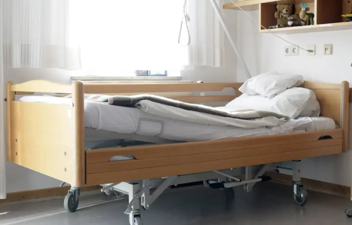 Ein Pflegebett mit Holzrahmen und Rädern, bereit, wenn Sie ein Pflegebett beantragen müssen.