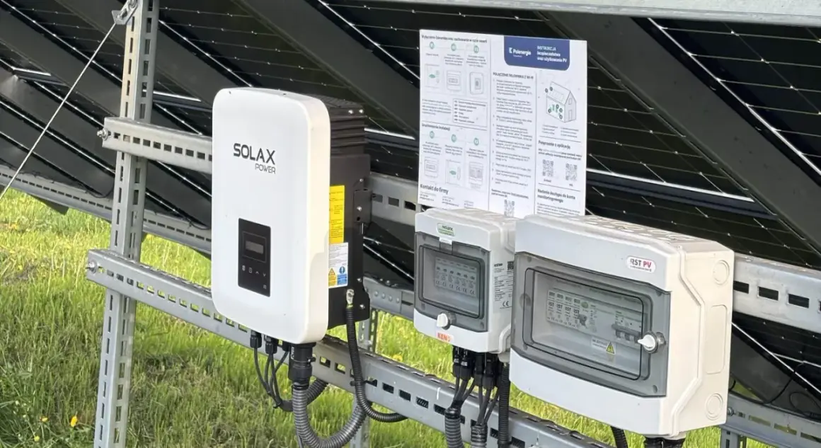 Falownik Solax Power i skrzynki przyłączeniowe na tle paneli PV. Zastanawiasz się, ile kosztuje wymiana falownika? Sprawdź instrukcje i kontakty.