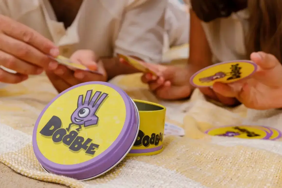 Gra w Dobble to szybkie szukanie wspólnych symboli na kartach. Dzieci i dorośli świetnie się bawią, ucząc się, jak się gra w Dobble.