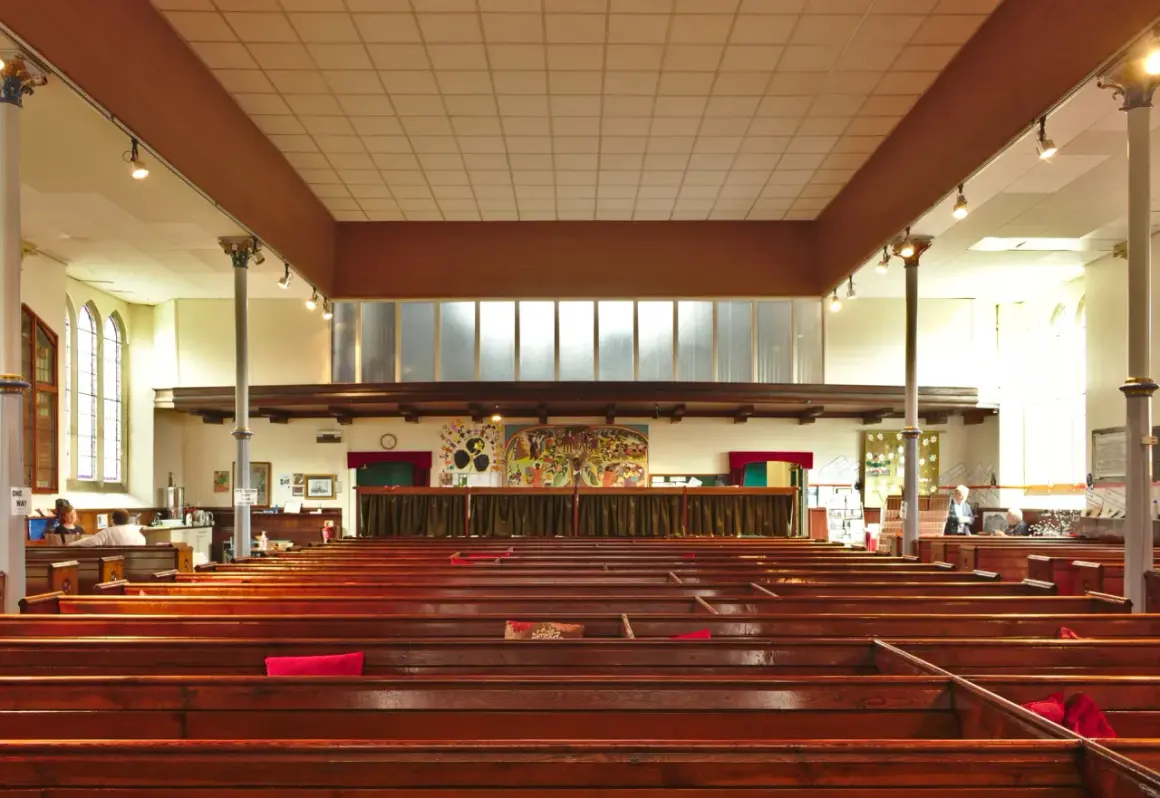 Intérieur d'une église protestante, avec des bancs en bois verni et une fresque colorée au mur. Un lieu paisible pour un baptême chez les protestants.