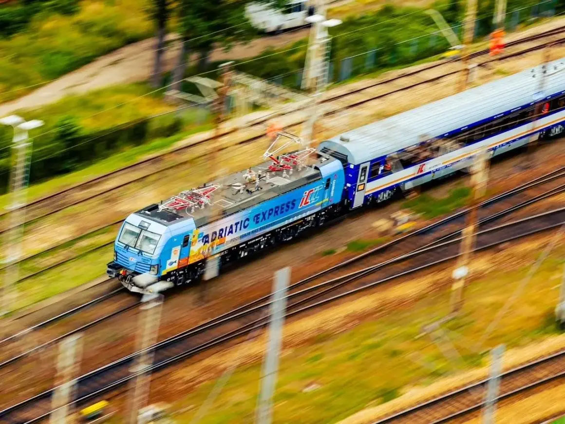Pędzący pociąg "Adriatic Express" na trasie z Warszawy do Łodzi, z rozmytym tłem zieleni i torów.