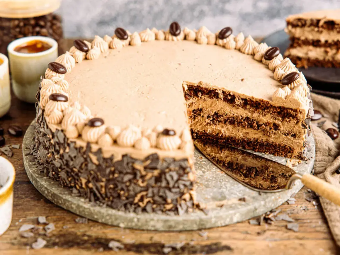 Eine köstliche Kaffee Torte mit Schokoladenraspeln und Kaffeebohnen-Dekoration. Ein Stück wurde bereits angeschnitten.