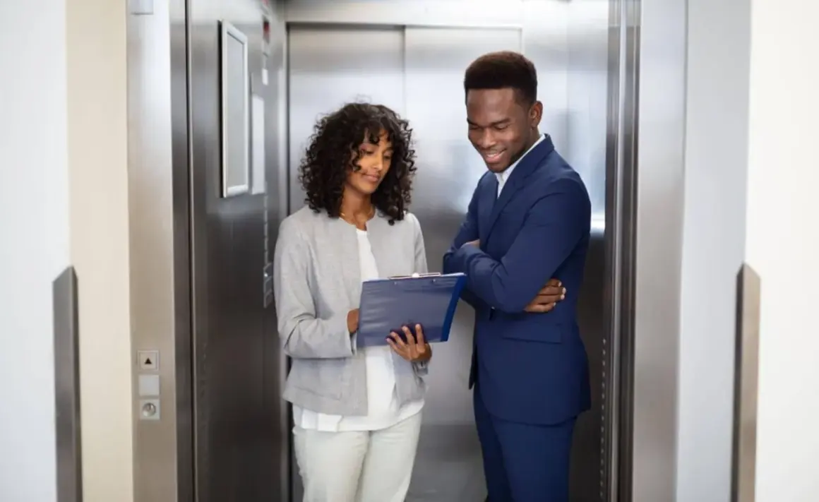 Zwei Geschäftsleute im Aufzug, die Notizen besprechen. Ein kurzer elevator pitch, bevor die Türen sich öffnen.