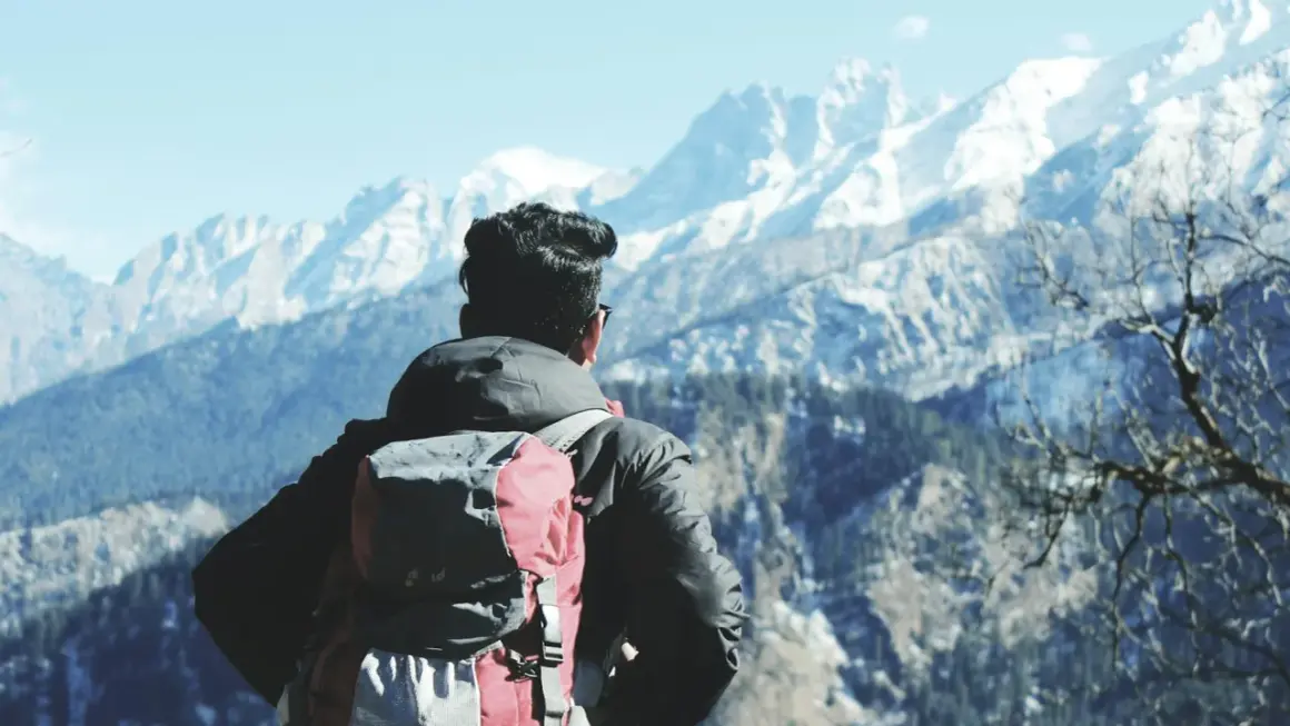 Wspaniała wycieczka do Indii! Mężczyzna z plecakiem podziwia ośnieżone szczyty Himalajów.