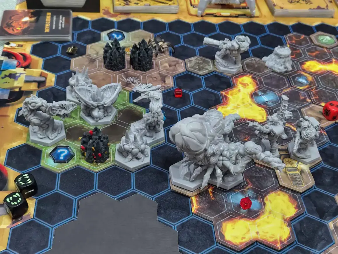 Das **Deep Rock Galactic Brettspiel** zeigt eine spannende Szene mit Zwergen-Miniaturen, Monstern und Würfeln auf einem hexagonalen Spielfeld.