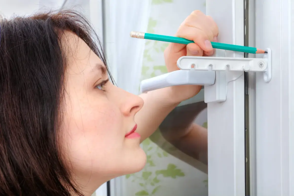 Une femme ajuste une vis de réglage sur une fenêtre PVC avec un crayon.