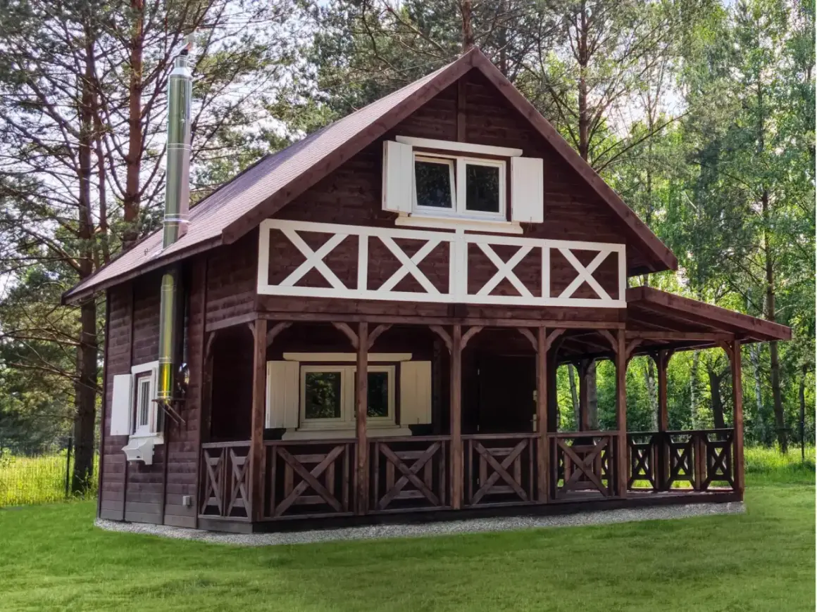 Urokliwy projekt dom kanadyjski z werandą i białymi okiennicami, otoczony zielenią.