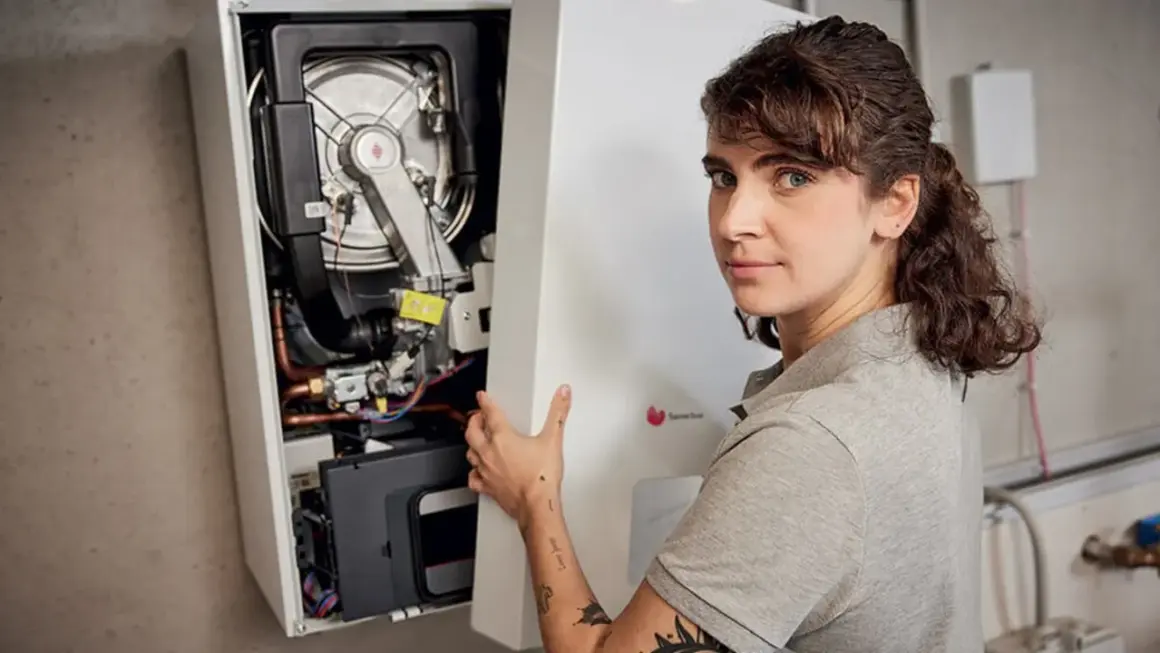 Une technicienne installe une chaudière F28. Elle tient le panneau avant ouvert, révélant les composants internes.