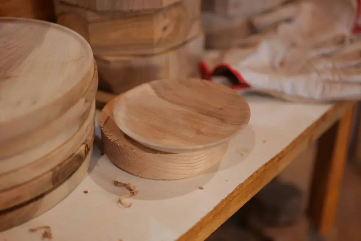 Assiette en bois brut sur un tour, avec des copeaux. Une belle idée de tournage sur bois pour créer des objets uniques.