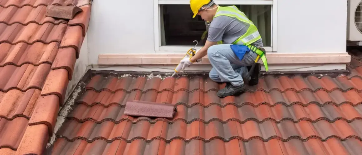 A roofer applies sealant to a shingle roof detail, ensuring a watertight seal around the window.