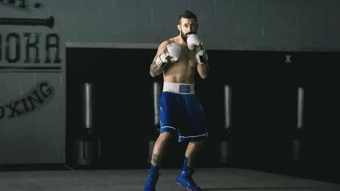 A boxer, ready to fight, demonstrates his switch hitter stance in a boxing gym.