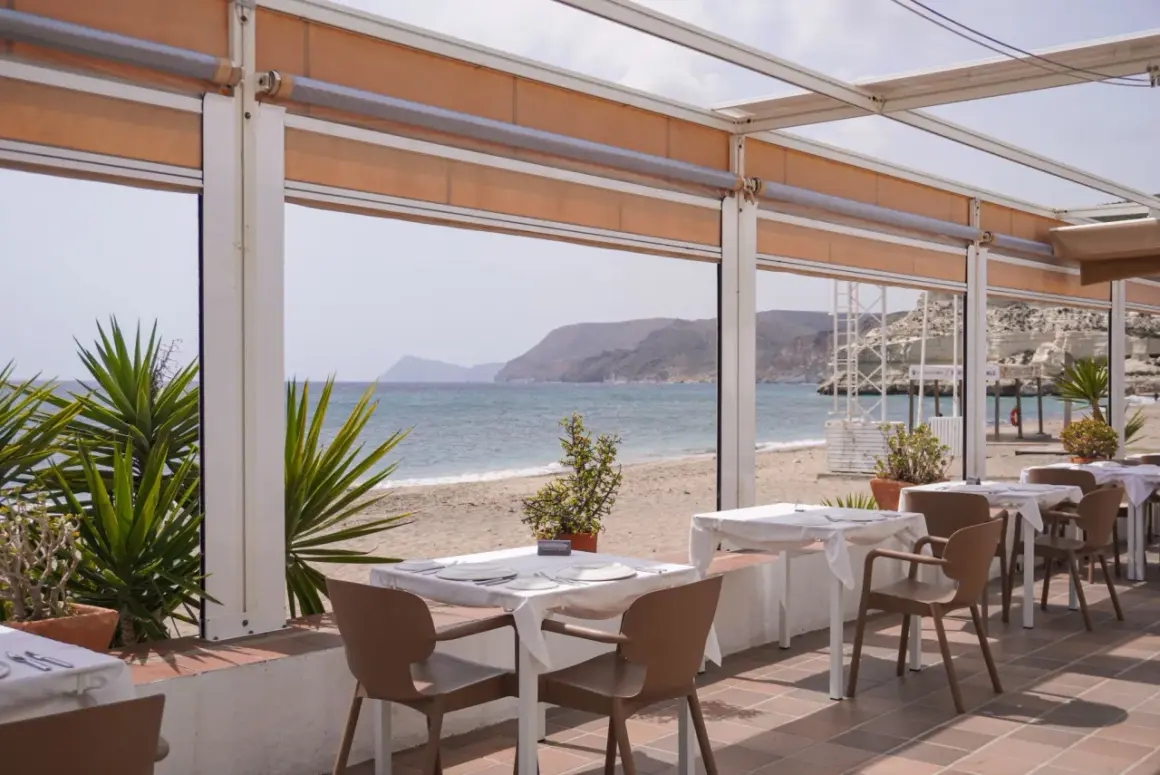Mesas listas para cenar en el asador La Chumbera, con vistas al mar y la playa.