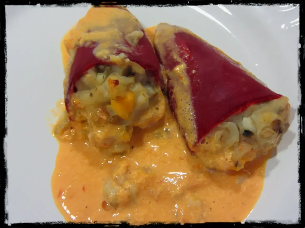 Dos pimientos del piquillo rellenos de gambas, cubiertos con una cremosa salsa rosada.