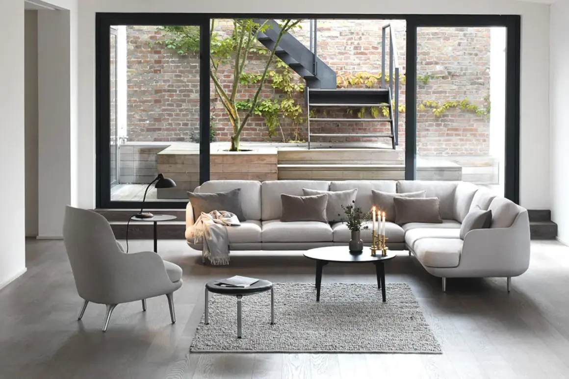 Modernes wohnzimmer mit 2 Sofas, einem Sessel und großem Fenster zum Garten mit Treppe.