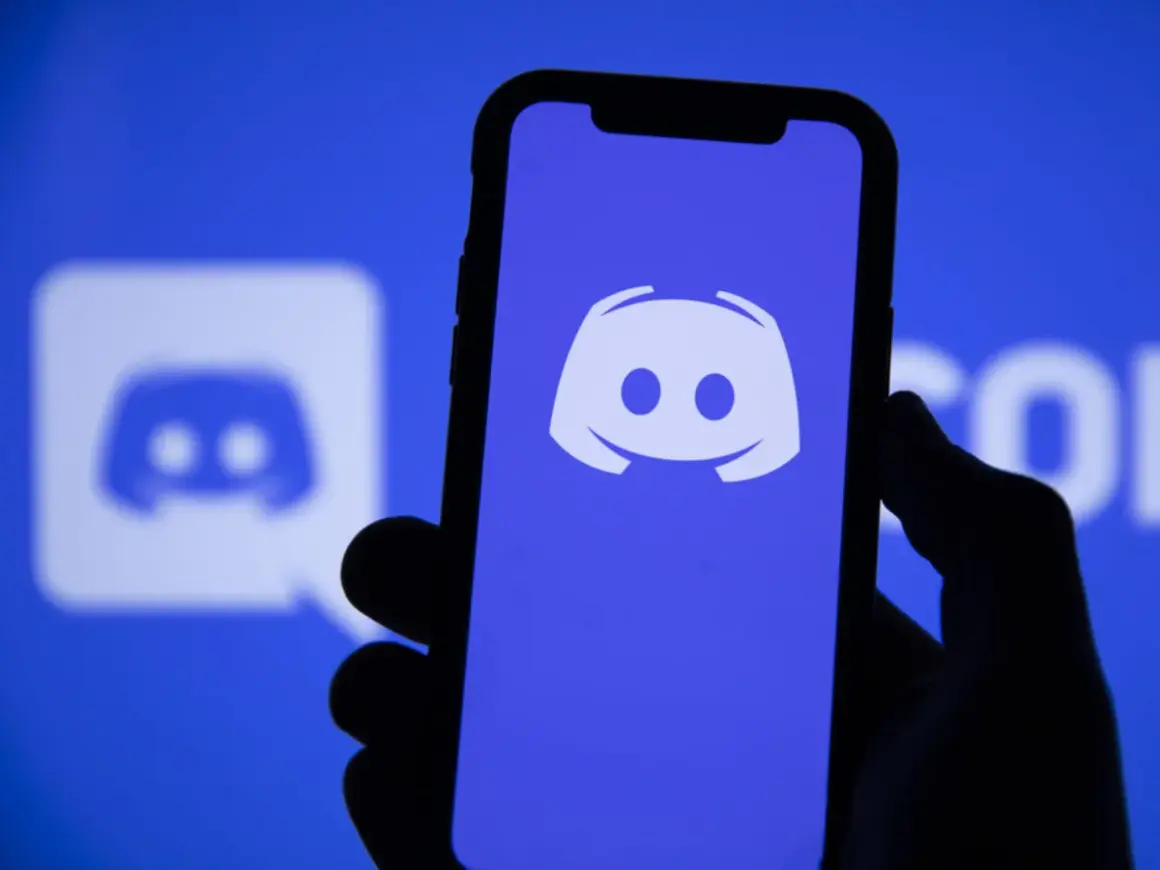 Dłoń trzyma smartfon z logo Discord. Aplikacja ta służy do komunikacji, więc jeśli zastanawiasz się "discord co to", to właśnie ją widzisz.