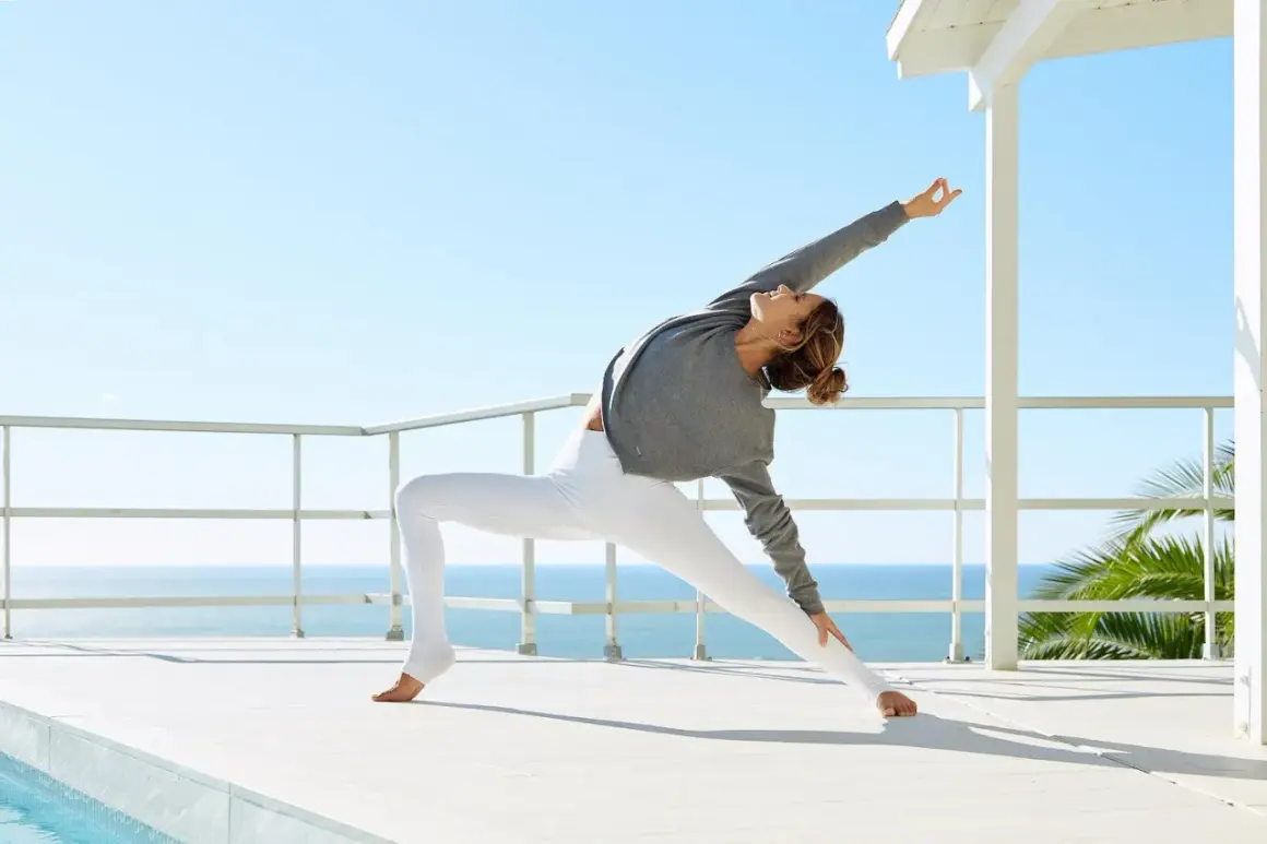 Mujer en postura de yoga expansiva, reflejando la esencia de jivamukti yoga que es.