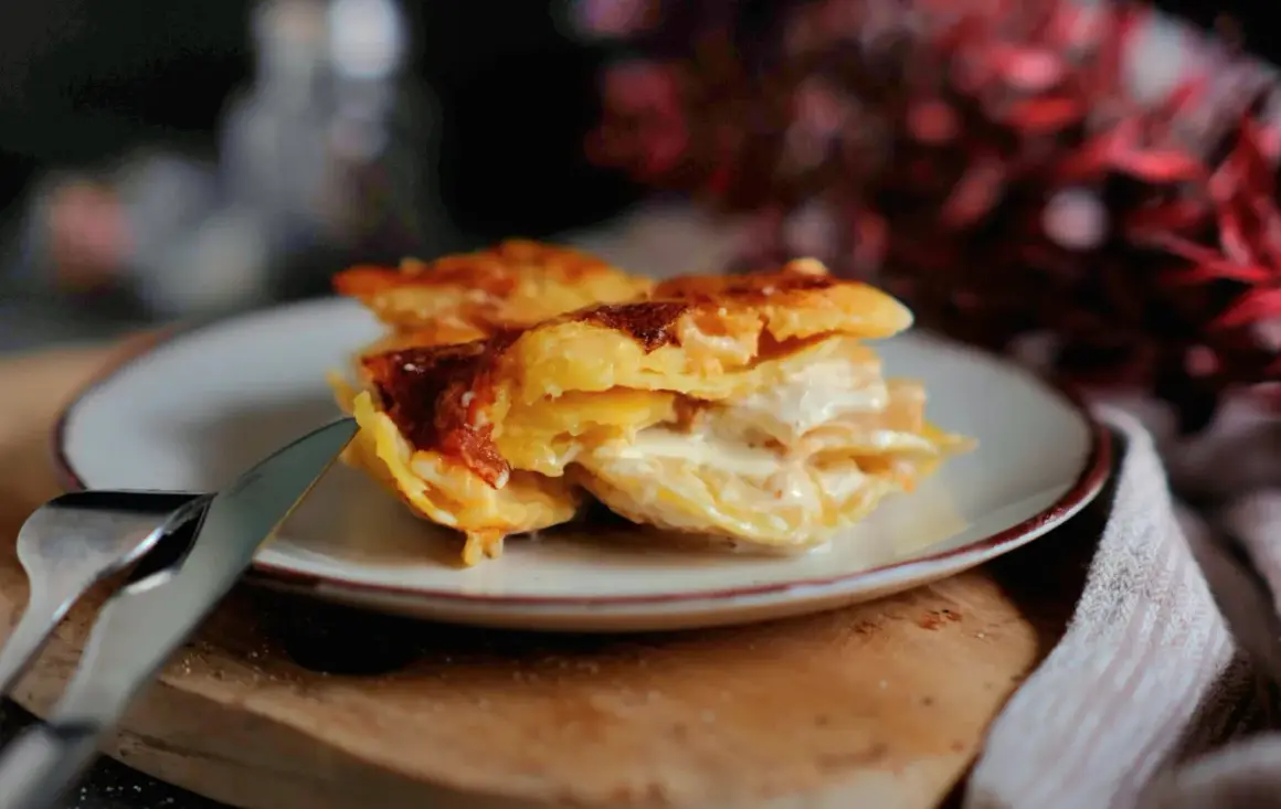 Ein Stück cremiges Kartoffelgratin mit goldbrauner Kruste auf einem Teller, bereit zum Genießen. Dieses Kartoffelgratin Rezept ist ein Genuss!