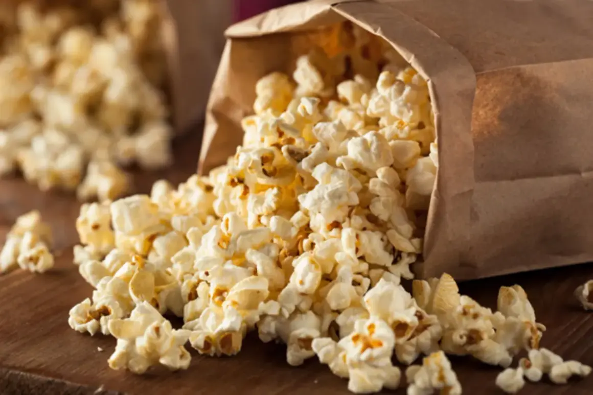Frischer Popcorn fließt aus einer Papiertüte. Perfekt für kalorienarme Snacks beim Filmabend.