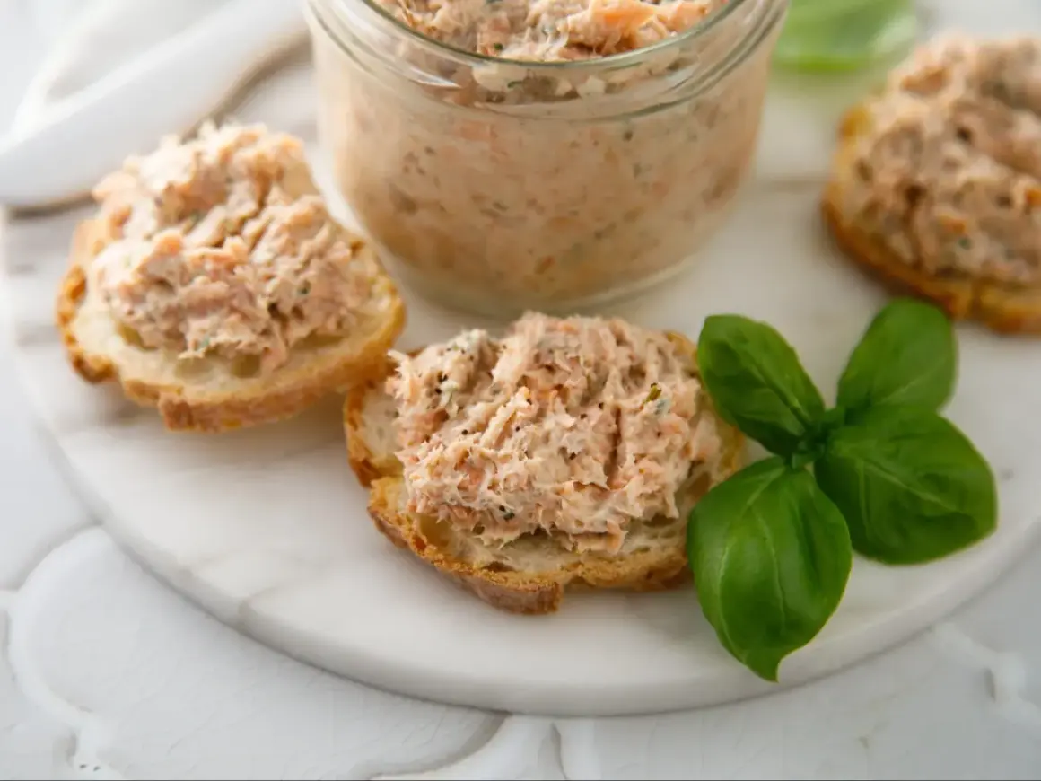 Pyszna pasta rybna na chrupiących grzankach, ozdobiona świeżą bazylią. Idealna na szybką przekąskę.
