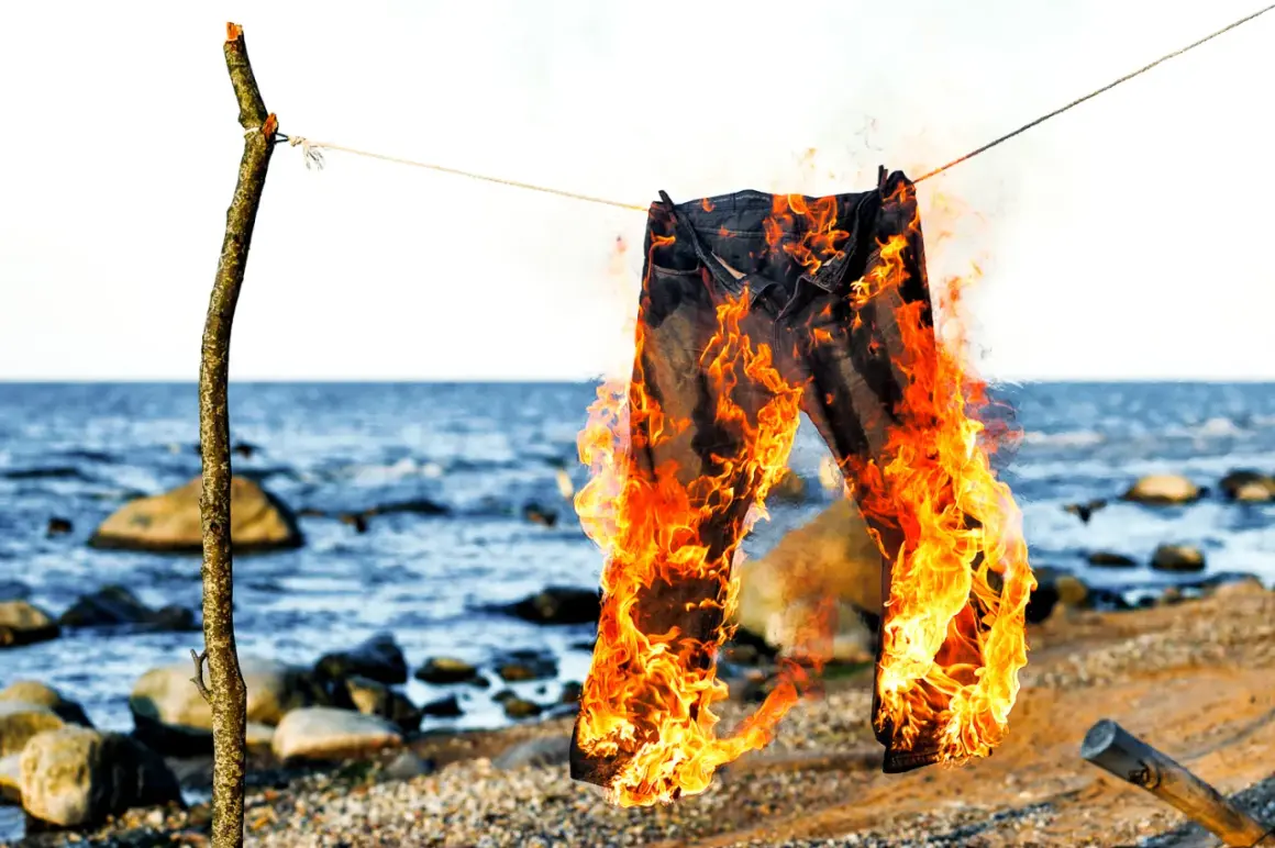 Jeans brennen am Strand, ein Symbol für den Polterabend. Die Flammen tanzen, während die Wellen rauschen.