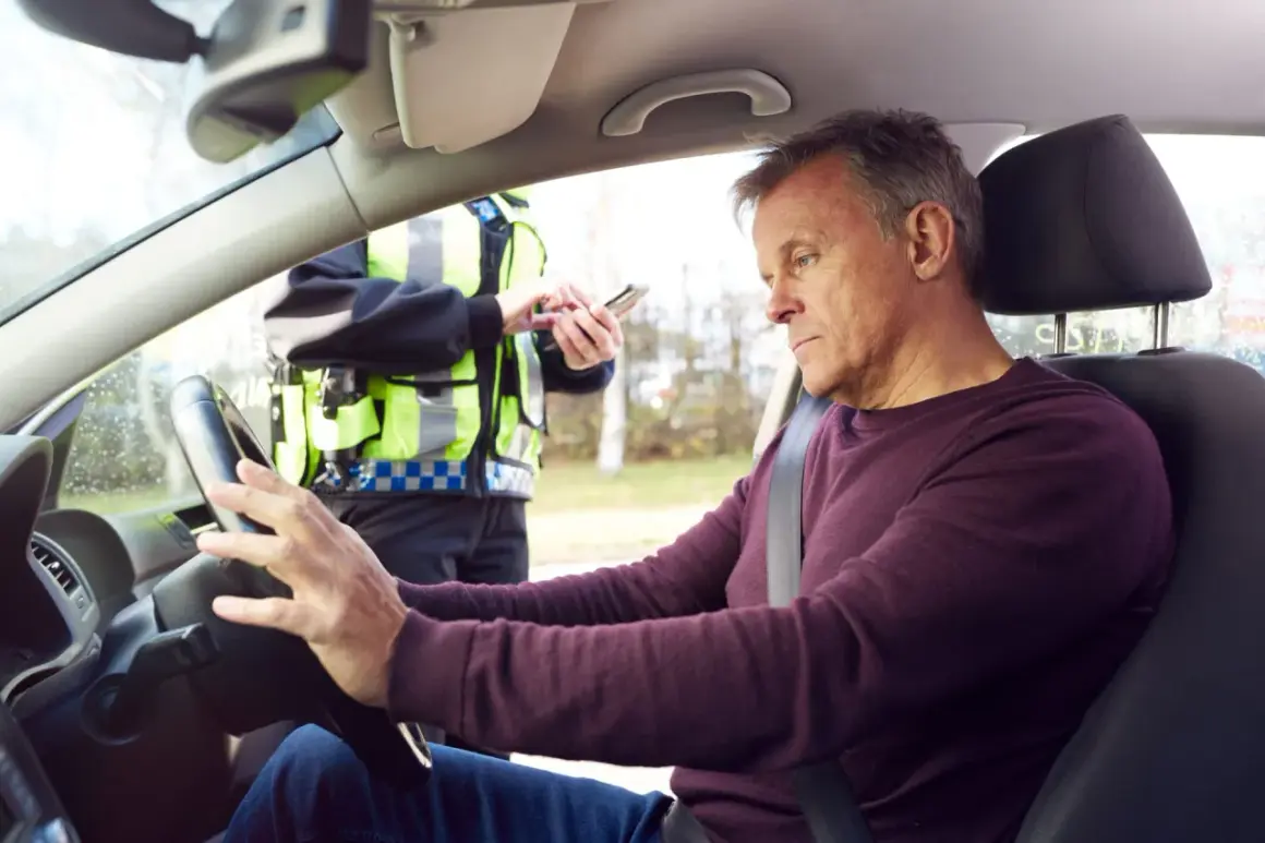 Mann am Steuer, Polizist mit Handy. Die Konsequenzen von Alkohol am Steuer sind eine empfindliche Strafe.