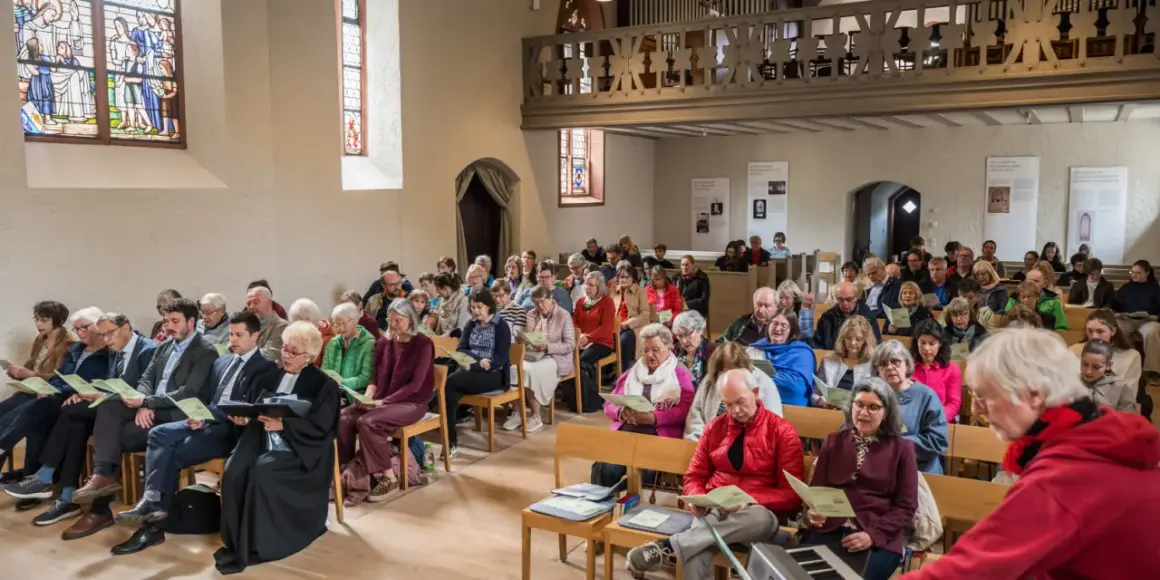 Menschen sitzen in einer Kirche und singen. Dies ist ein Beispiel dafür, was ist eine Freikirche: eine Gemeinschaft, die sich selbst organisiert.