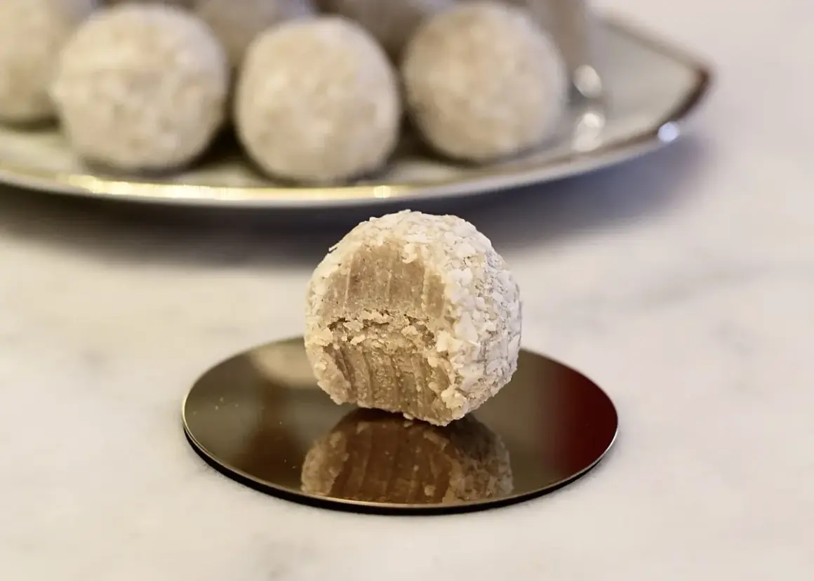 En bit tagen ur en av de fluffiga vita chokladbollarna, som är rullade i kokosflingor.